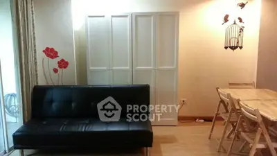 Cozy living room with black sofa and wooden dining set, perfect for modern living.