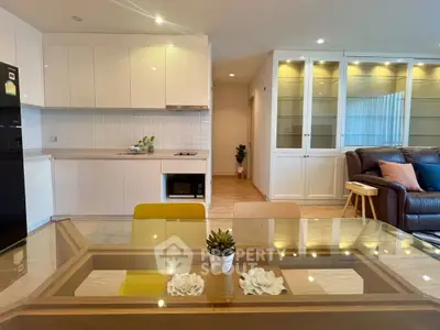 Modern open-layout kitchen and living room with stylish decor and glass dining table.