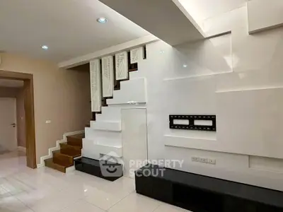 Modern interior with sleek staircase and wall-mounted TV setup in a stylish living room.