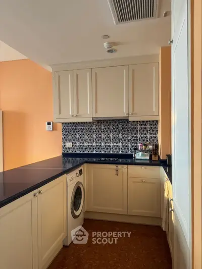 Charming kitchen with closed layout and modern appliances, featuring elegant cabinetry and stylish backsplash.