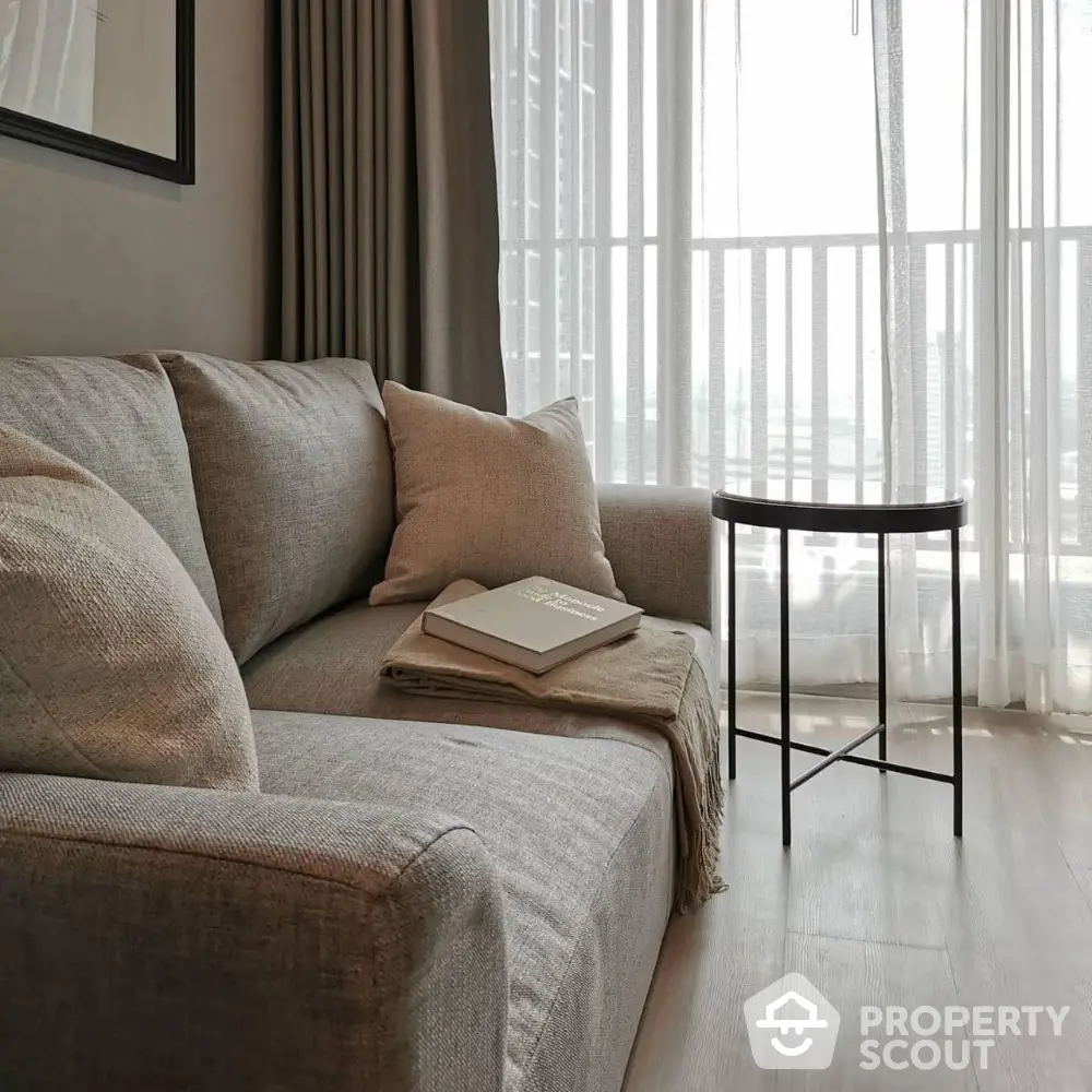 Modern living room with cozy gray sofa and stylish side table near balcony.