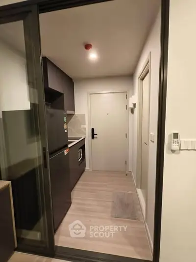 Modern compact kitchen with sleek appliances and minimalist design in a cozy apartment.