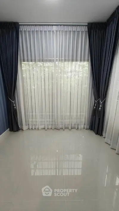 Elegant empty room with large window and luxurious curtains, perfect for customization.