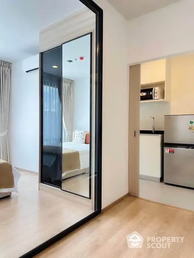 Modern studio apartment with mirrored wardrobe and compact kitchen