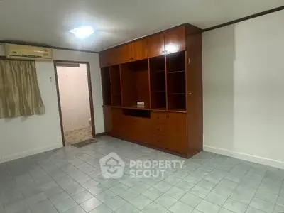 Spacious room with built-in wooden cabinets and tiled flooring, ideal for versatile living space.