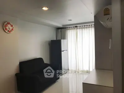 Modern living room with sleek black sofa and fridge, bright natural light through large window.