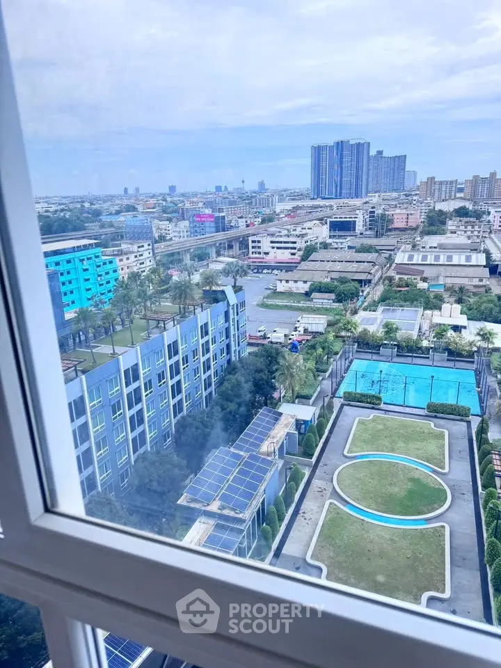 Stunning cityscape view from high-rise apartment window overlooking modern buildings and lush greenery.