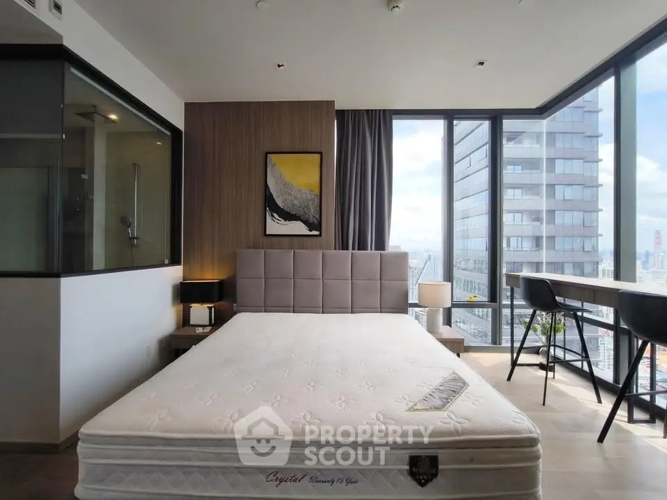 Modern bedroom with large windows offering city views, featuring a stylish bed and contemporary decor.