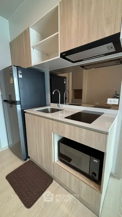 Modern kitchen with sleek appliances and wooden cabinetry in a compact layout.