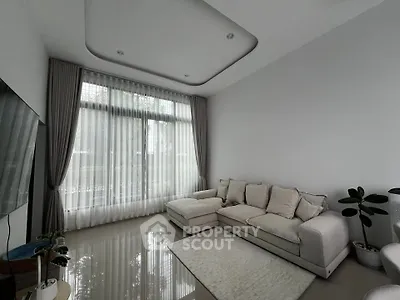 Modern living room with elegant sofa and large window, featuring stylish decor and natural light.