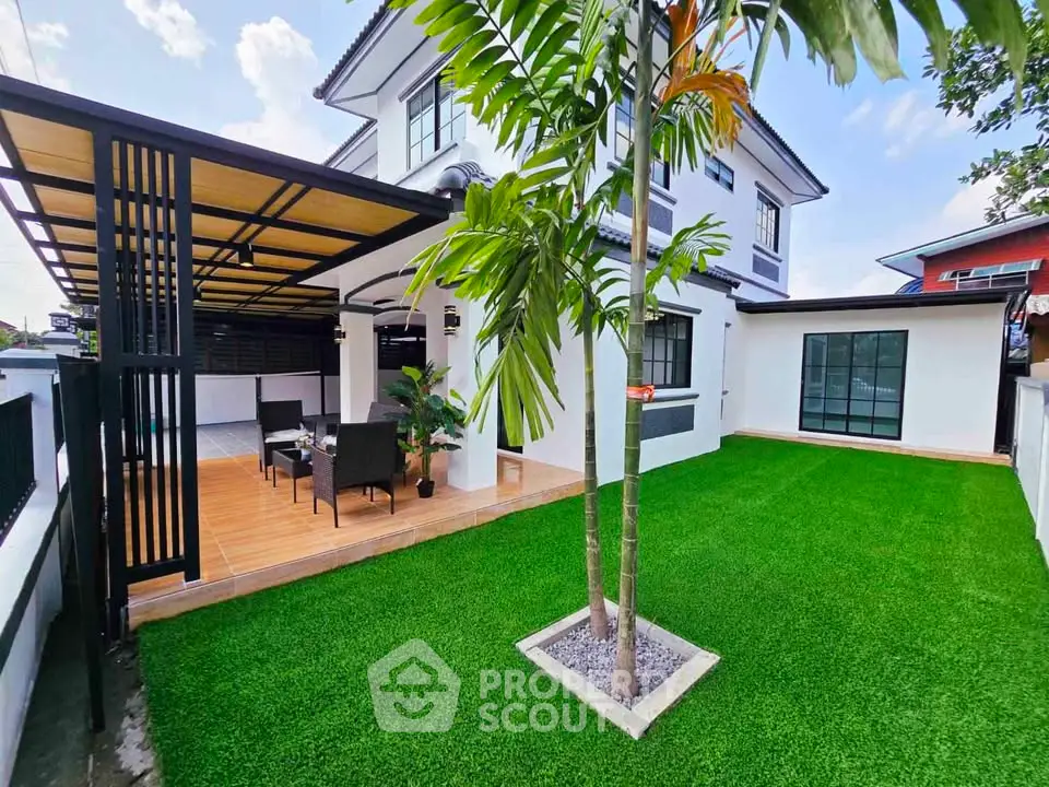 Stunning modern home with lush green garden and stylish outdoor seating area, perfect for relaxation.