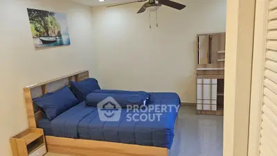 Cozy bedroom with modern wooden furniture and blue bedding, perfect for relaxation.