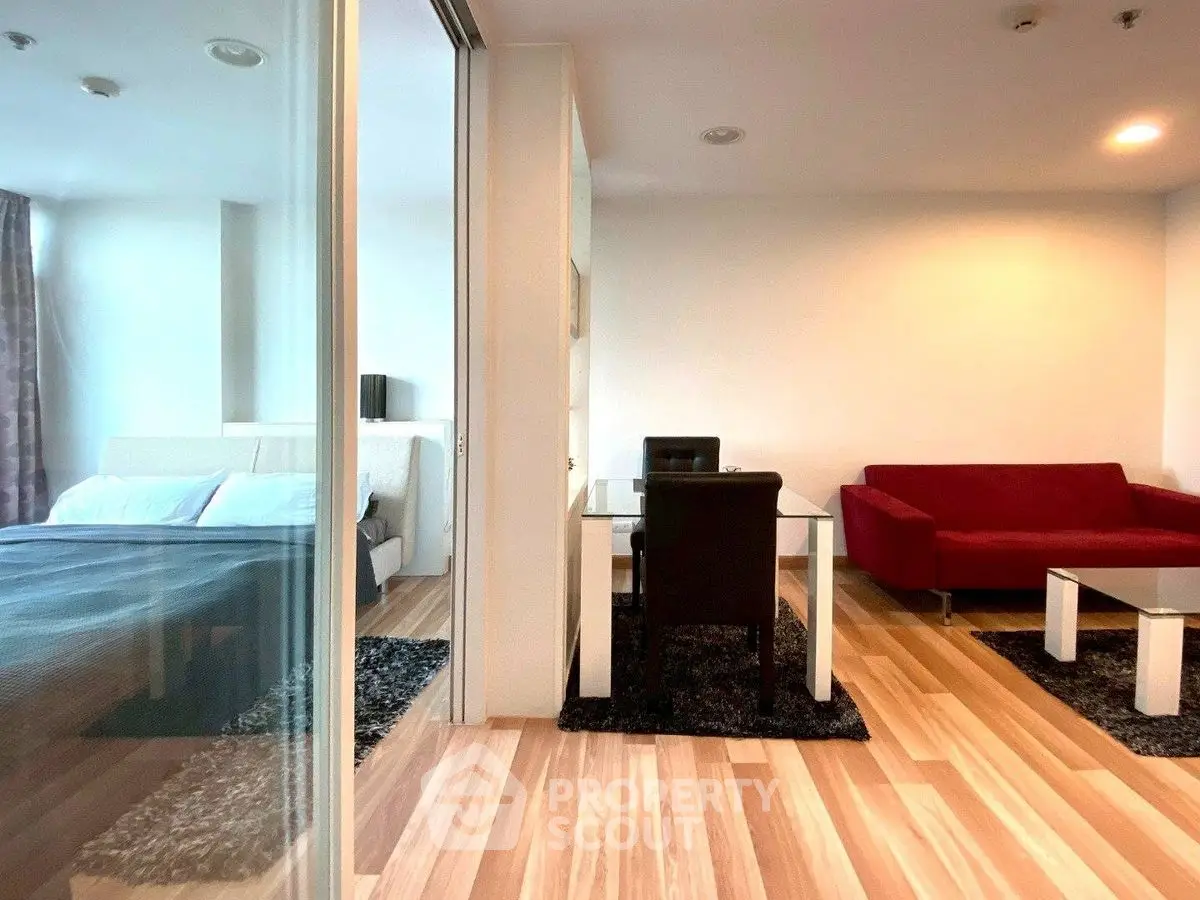 Modern apartment with glass partition, cozy living area, and stylish bedroom.