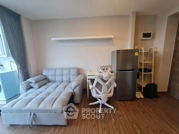 Modern living room with stylish sofa, sleek fridge, and elegant wooden flooring.