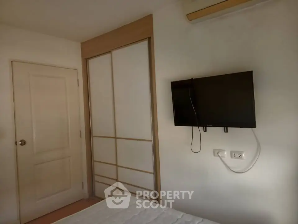 Cozy bedroom with wall-mounted TV and sliding closet doors, perfect for modern living.