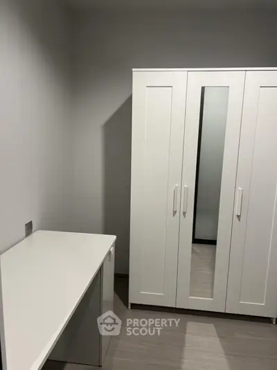 Minimalist bedroom with white wardrobe and desk, perfect for modern living.