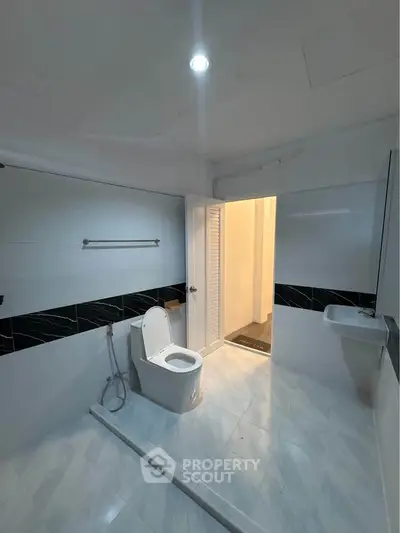 Spacious modern bathroom with sleek design and elegant fixtures, featuring a toilet and sink.