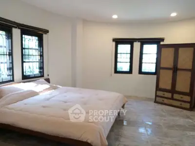 Spacious bedroom with large windows and elegant wardrobe in a serene setting.