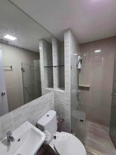 Modern bathroom with sleek design, featuring glass shower and stylish tiles.