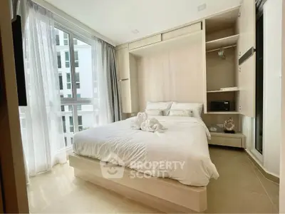 Modern bedroom with elegant decor and large windows in a high-rise apartment.