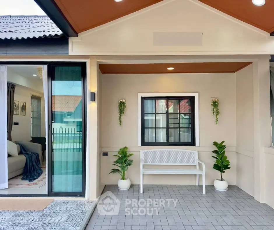 Charming modern home entrance with cozy seating and lush plants, inviting ambiance for relaxation.