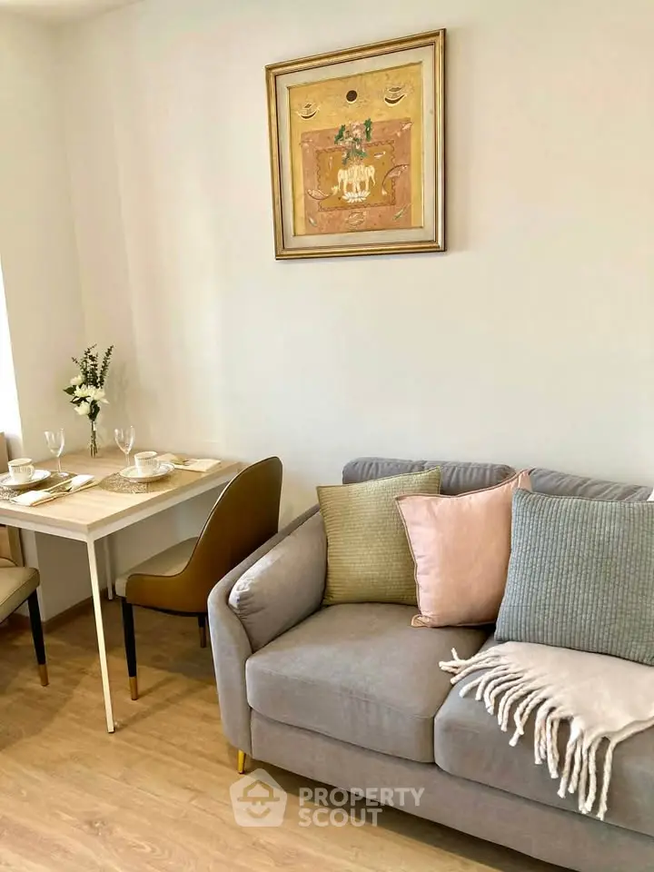 Cozy living room with stylish decor and dining area, featuring a comfortable sofa and elegant wall art.