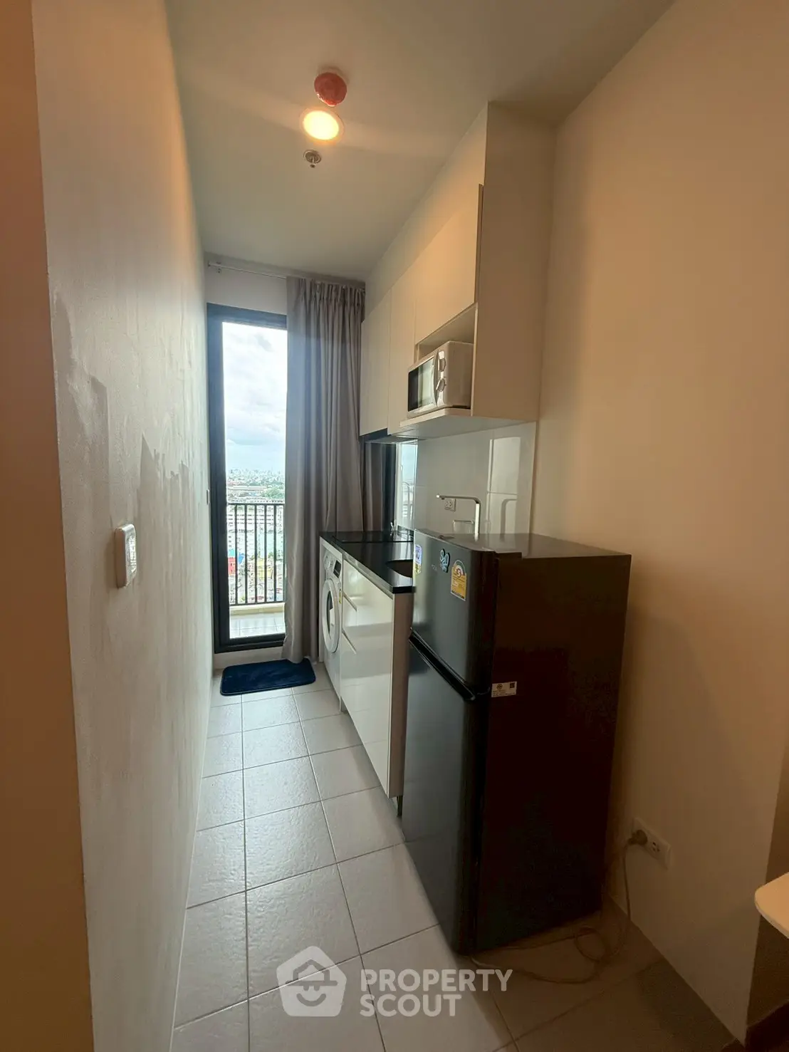 Modern kitchen with appliances and balcony view in compact apartment.