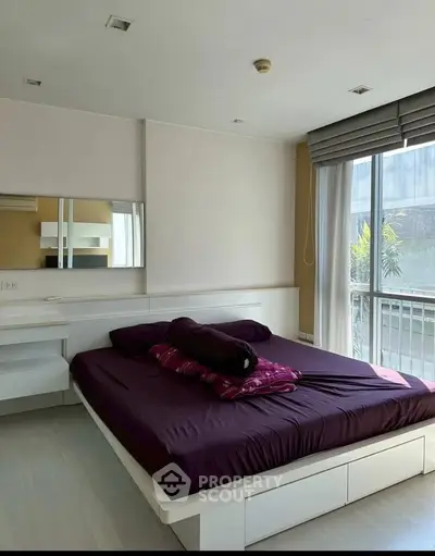 Modern bedroom with large window and stylish decor in a contemporary apartment.