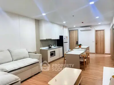 Modern open-plan living room and kitchen with sleek furniture and wooden flooring.