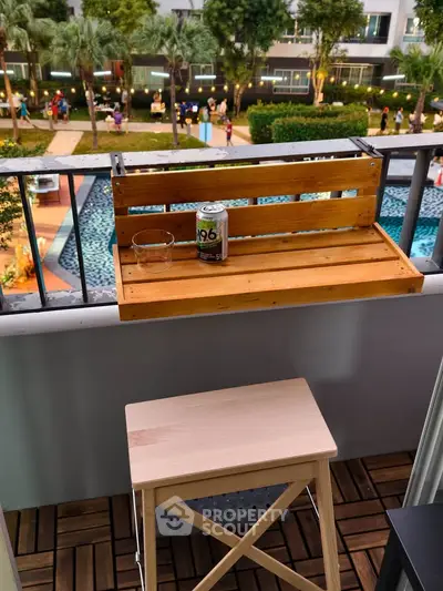 Charming balcony with wooden bar table overlooking lush garden and pool area, perfect for relaxation.
