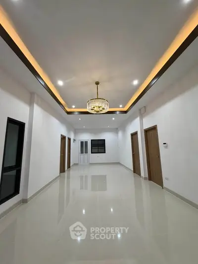 Spacious modern living room with elegant chandelier and glossy tiled flooring.