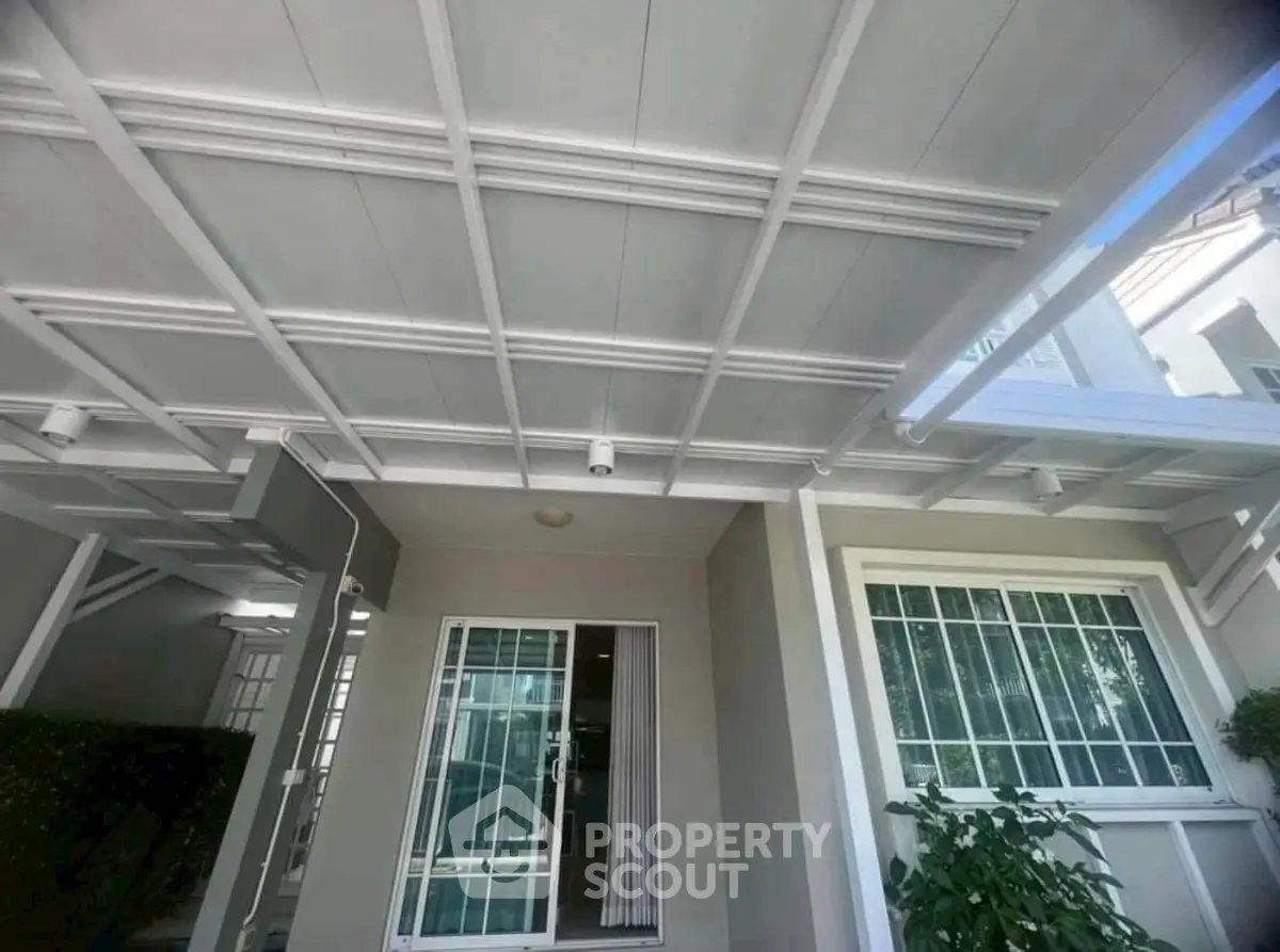 Modern exterior with sleek white pergola and large windows, perfect for natural light.