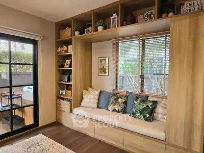Cozy living room with built-in seating and large window overlooking lush greenery.