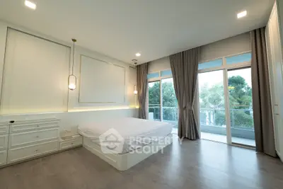 Spacious bedroom with large windows and balcony access in modern apartment