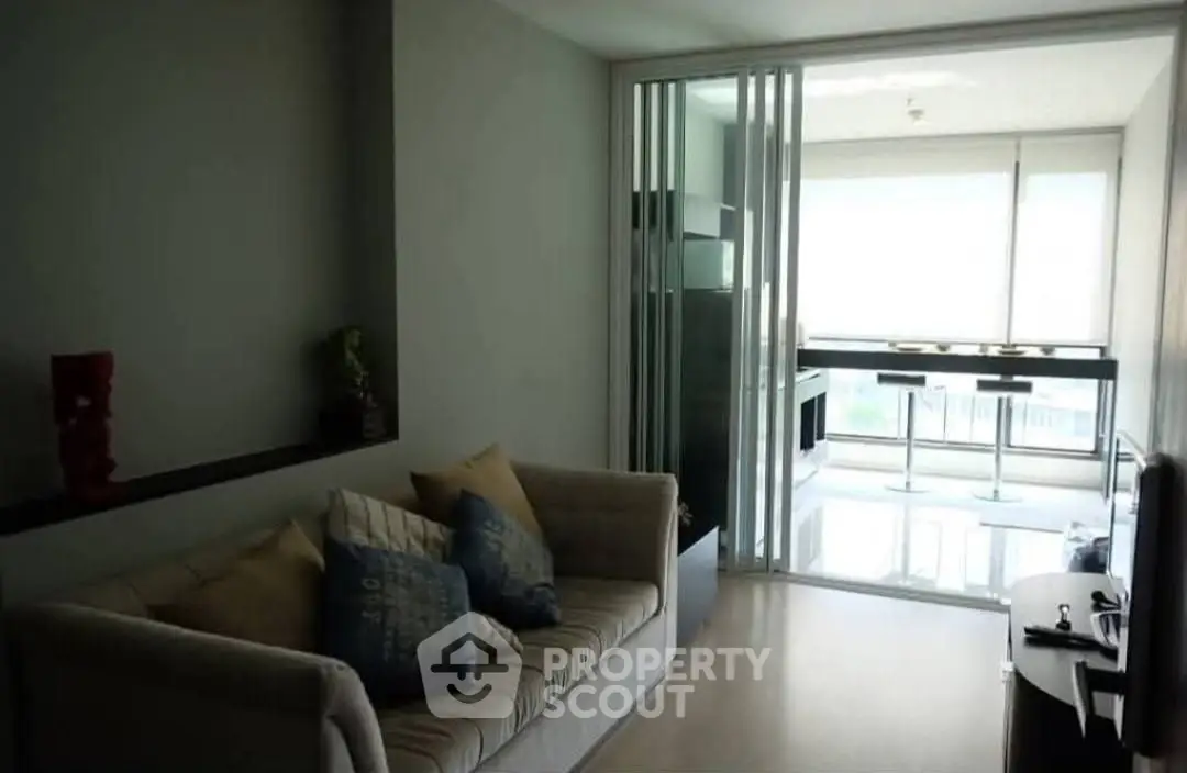 Modern living room with cozy sofa and sliding glass doors leading to a bright dining area.