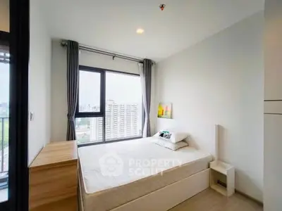 Modern bedroom with large window and city view in high-rise apartment.