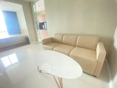Modern living room with beige sofa and sleek white coffee table in bright apartment.