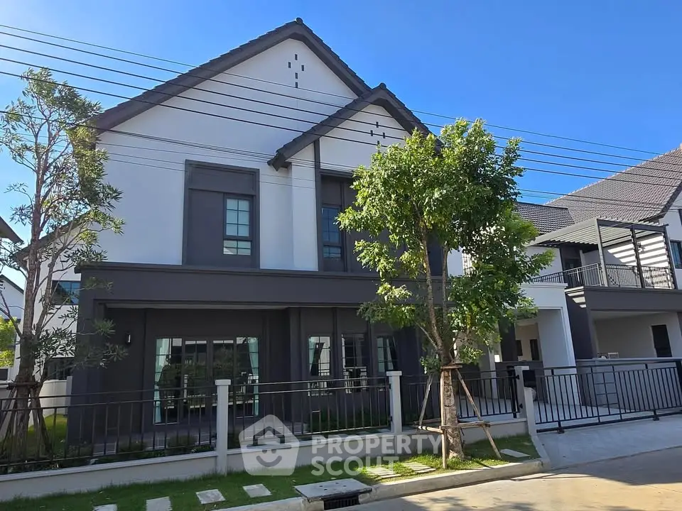 Modern two-story house with sleek design and lush greenery in a serene neighborhood.