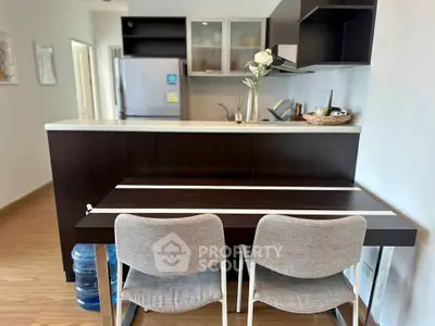 Modern kitchen with sleek design and dining area, featuring stylish chairs and a spacious fridge.