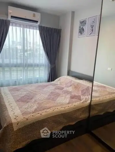 Cozy bedroom with large window and mirrored wardrobe in modern apartment.