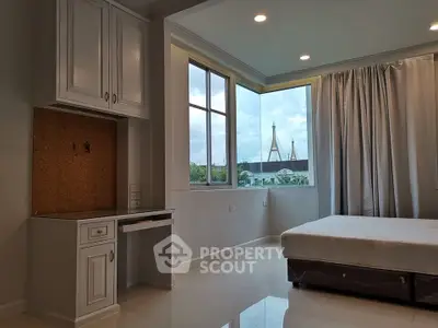 Spacious bedroom with large windows offering a stunning city view, perfect for relaxation and comfort.