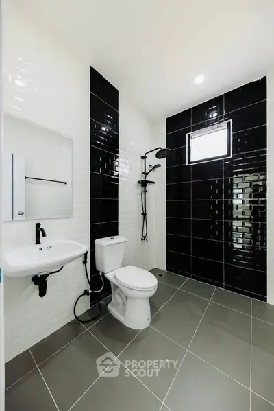 Modern bathroom with sleek black and white tiles and contemporary fixtures.