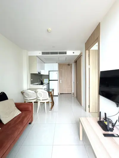 Modern living room with open kitchen layout and sleek furnishings in a bright apartment.