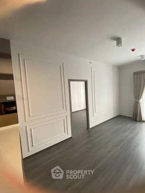 Spacious modern living room with elegant wall paneling and large window for natural light.