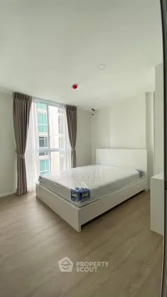 Spacious bedroom with large window and modern furnishings in a bright apartment.