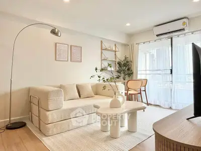 Modern living room with stylish decor, cozy sofa, and natural light from large windows.