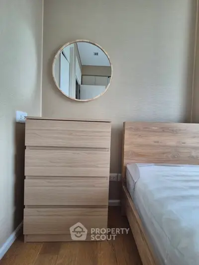 Modern bedroom with wooden furniture and round mirror, showcasing minimalist design.