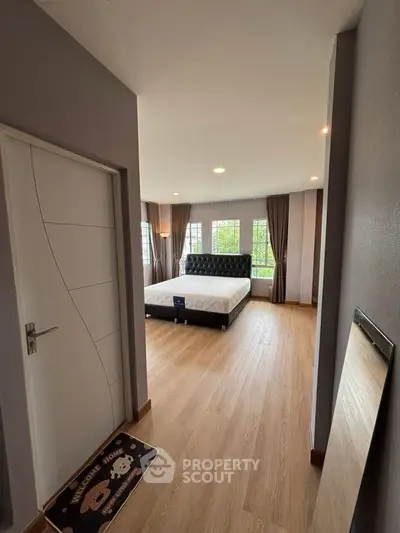 Spacious bedroom with modern decor and large windows for natural light.