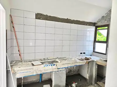 Under-construction kitchen with tiled walls and large window