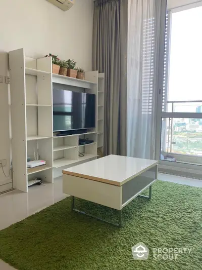 Bright and airy living room with plush green carpet, modern entertainment unit, and floor-to-ceiling window drapes, offering a cozy urban retreat.